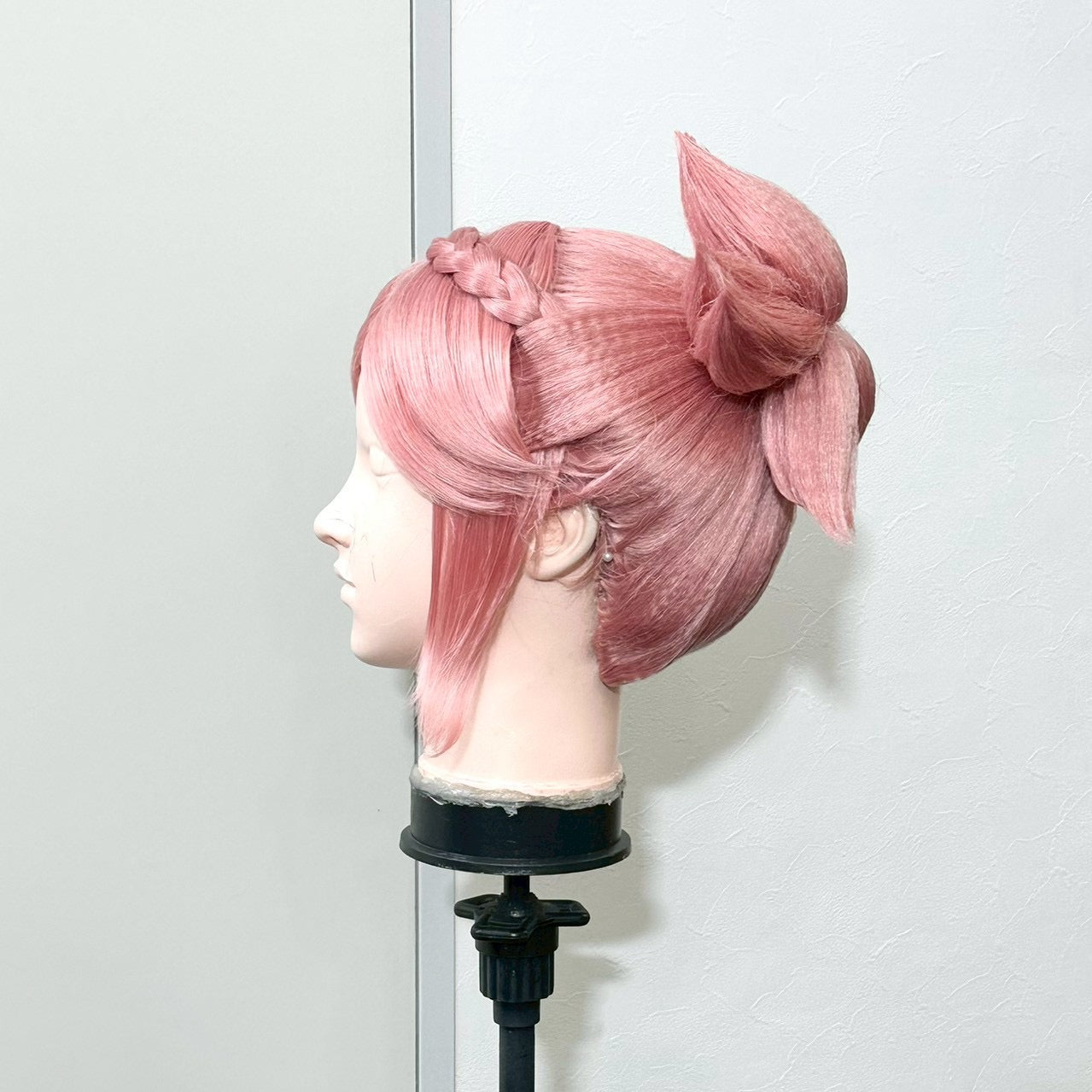 Pink updo wig on a mannequin head, seen in profile from the side