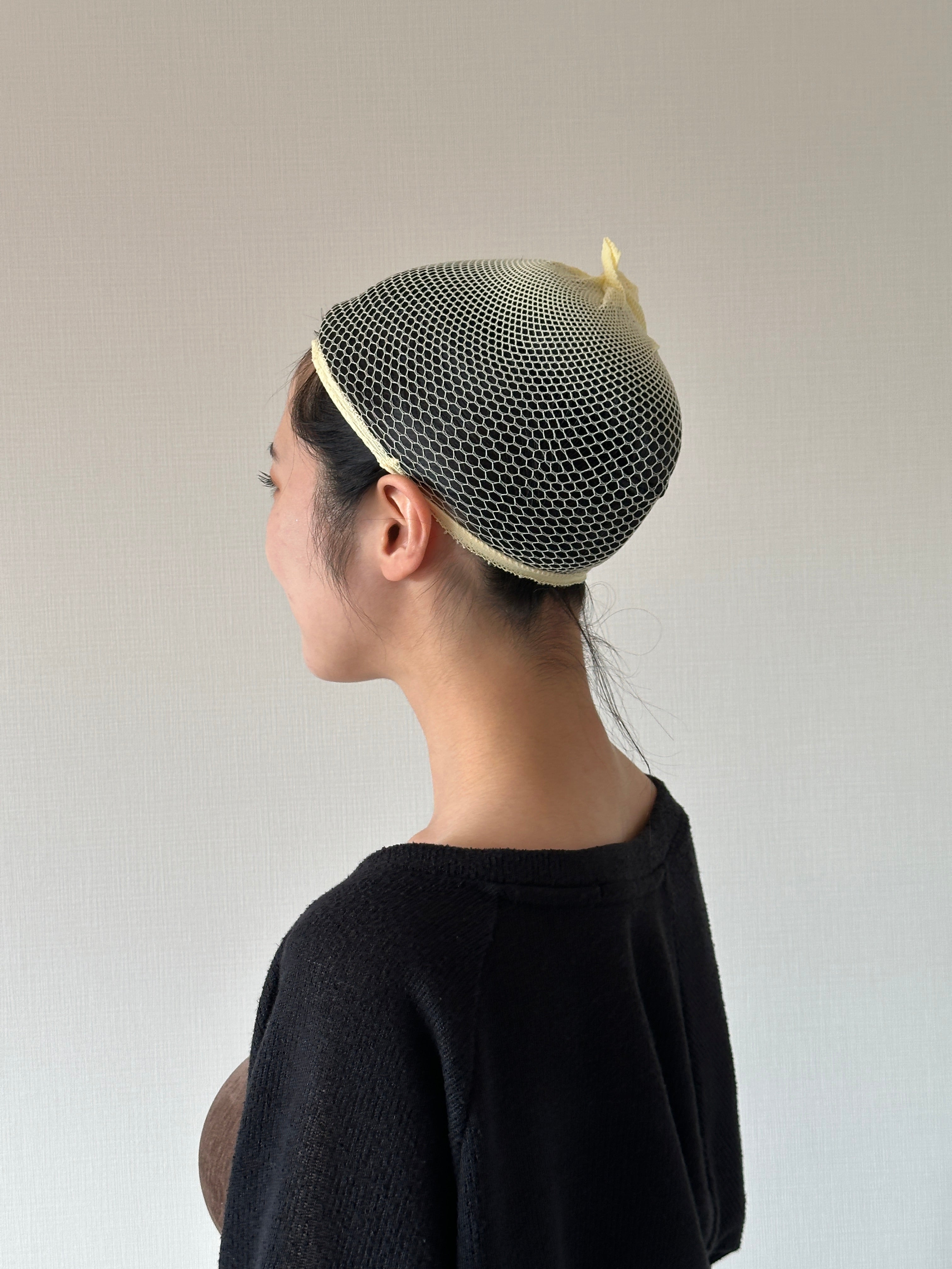A wig net fitted over the back of the head, showing the hairline and nape used for fit