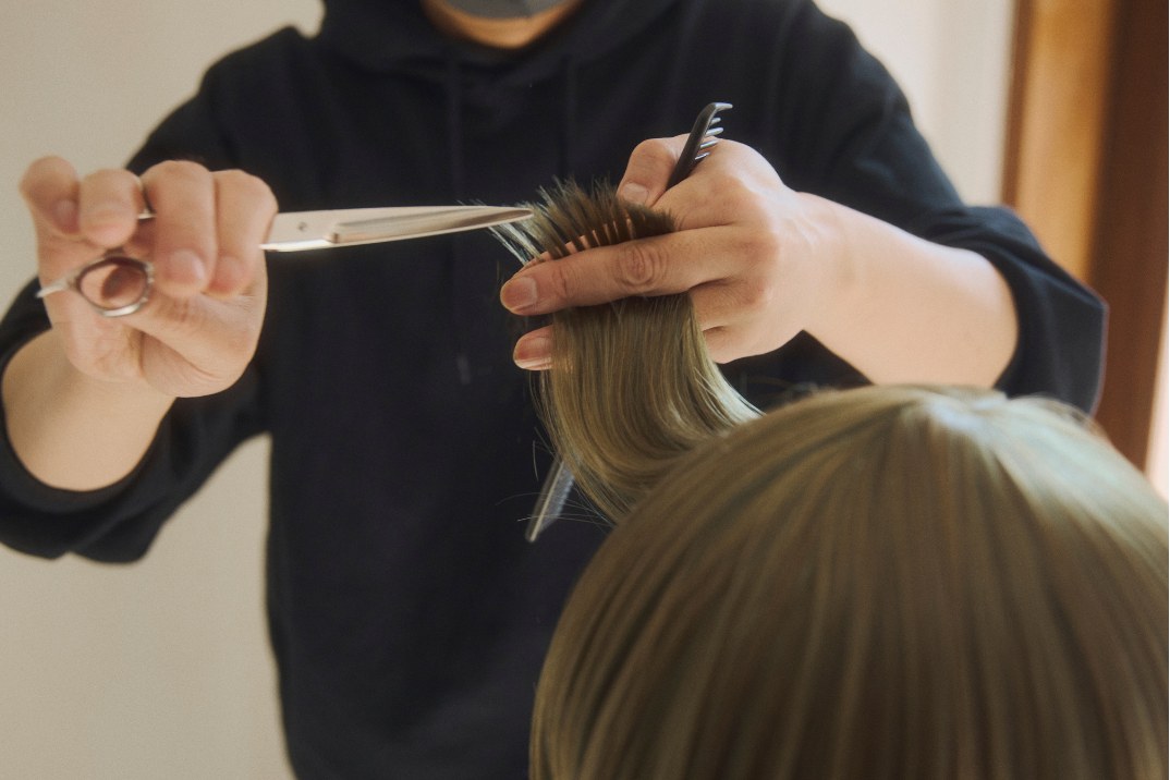 Hands cutting a section of fiber with scissors and a comb